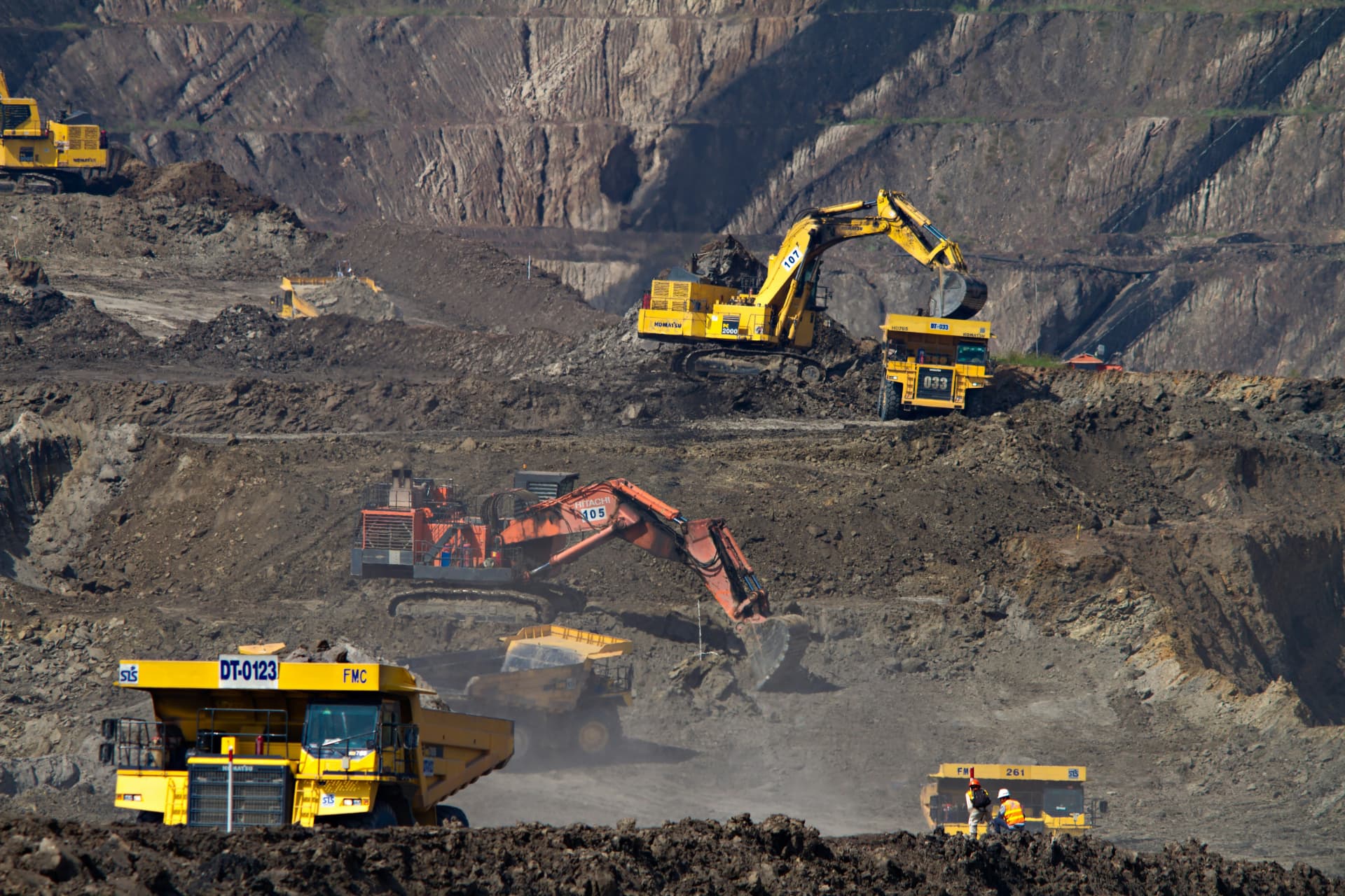 Open-pit mine with excavators and haul trucks working benched terraces