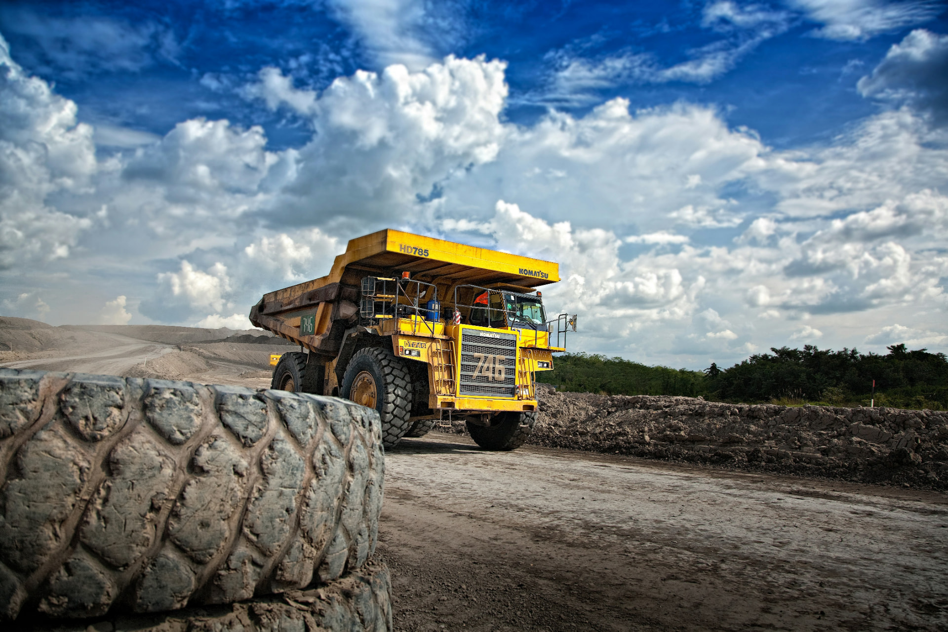 Yellow articulated haul truck on a mine haul road under cloud cover